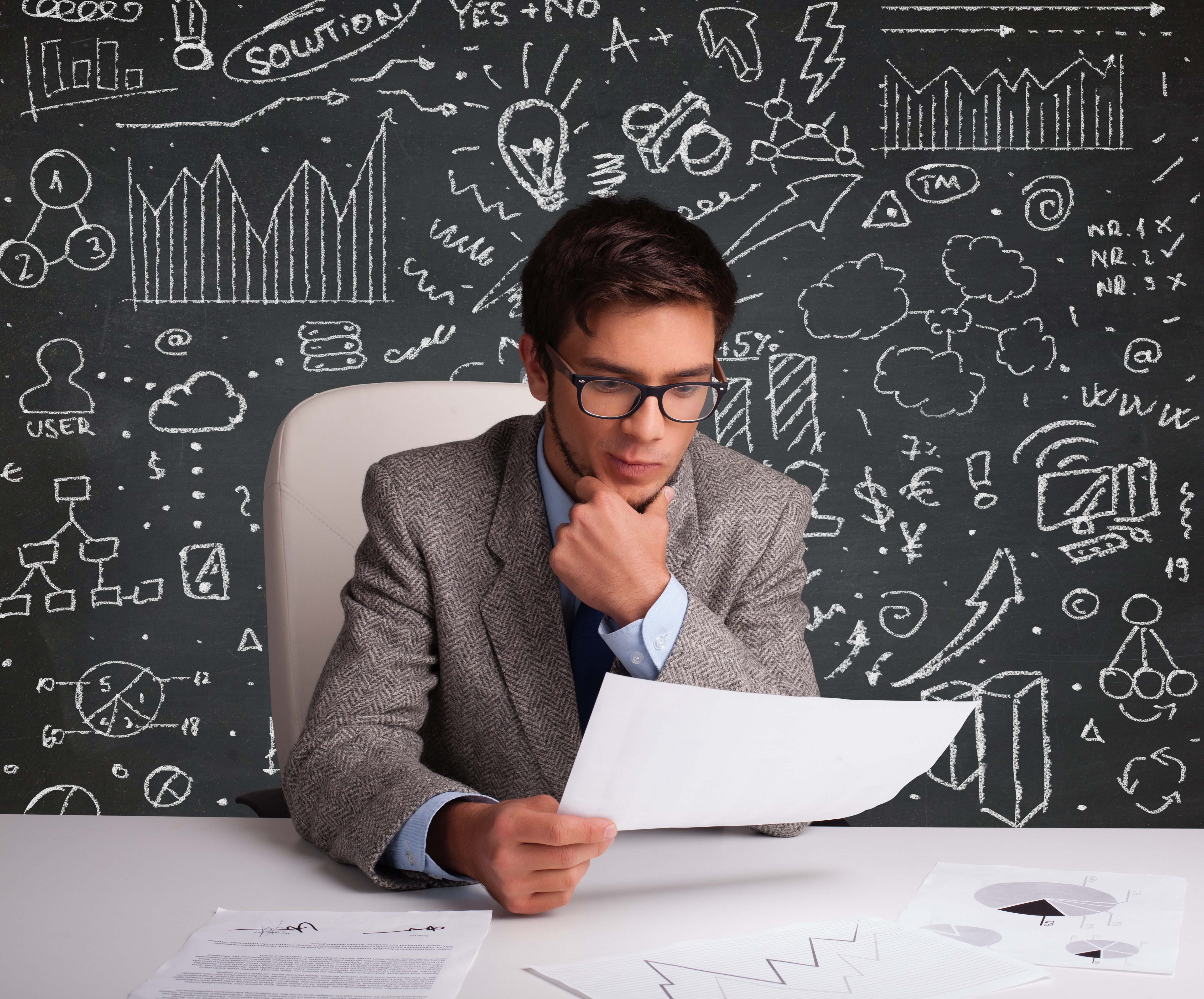 Businessman sitting at desk with business scheme and icons